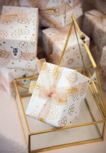 Elegant gift box with floral wrapping paper and ribbon on glass holder; perfect for celebrations.