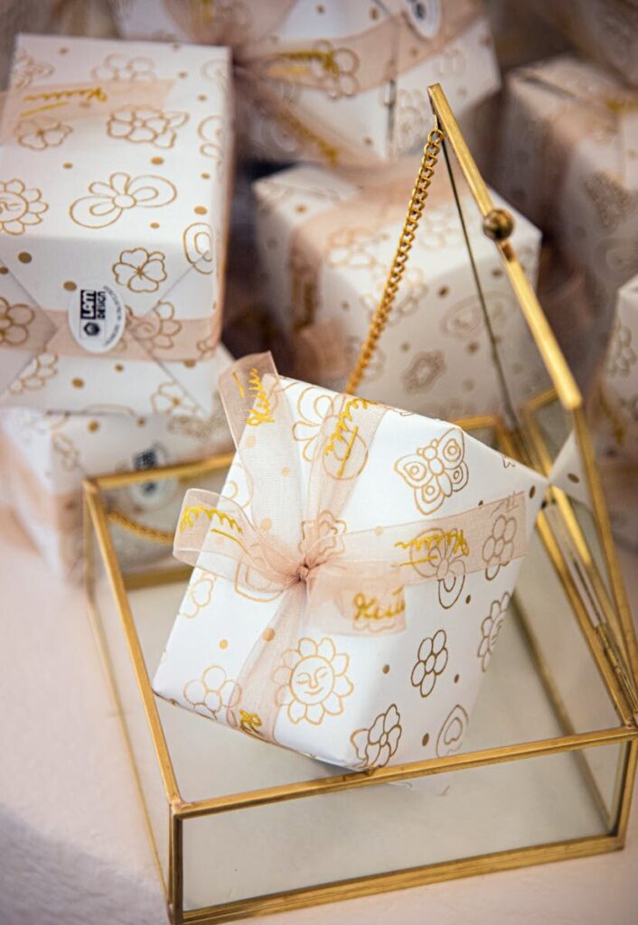 Elegant gift box with floral wrapping paper and ribbon on glass holder; perfect for celebrations.