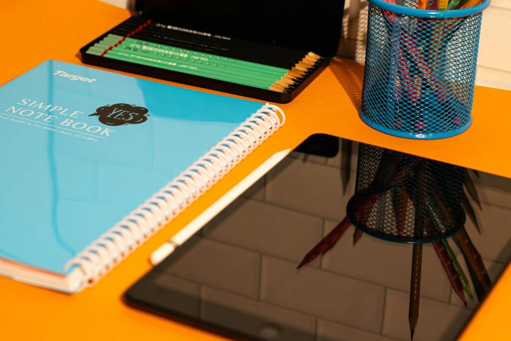 Colorful school supplies including notebook, pencil case, and tablet on a desk.