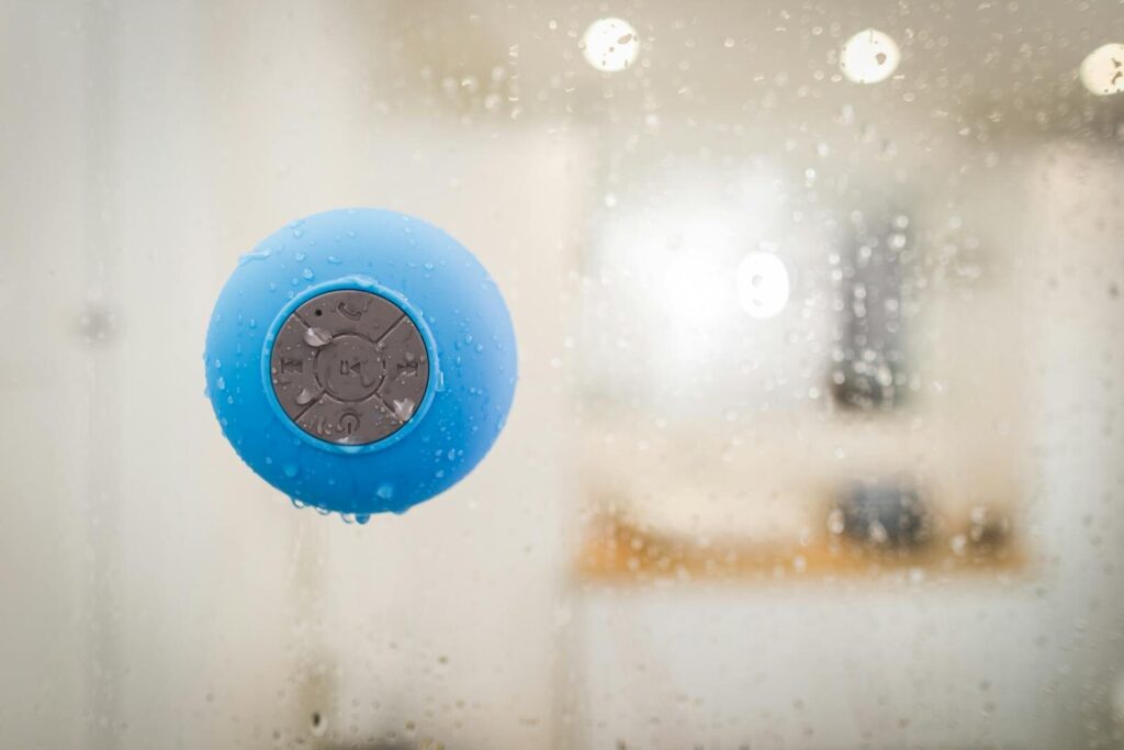 Close-up of a blue Bluetooth speaker with water droplets, ideal for showers.