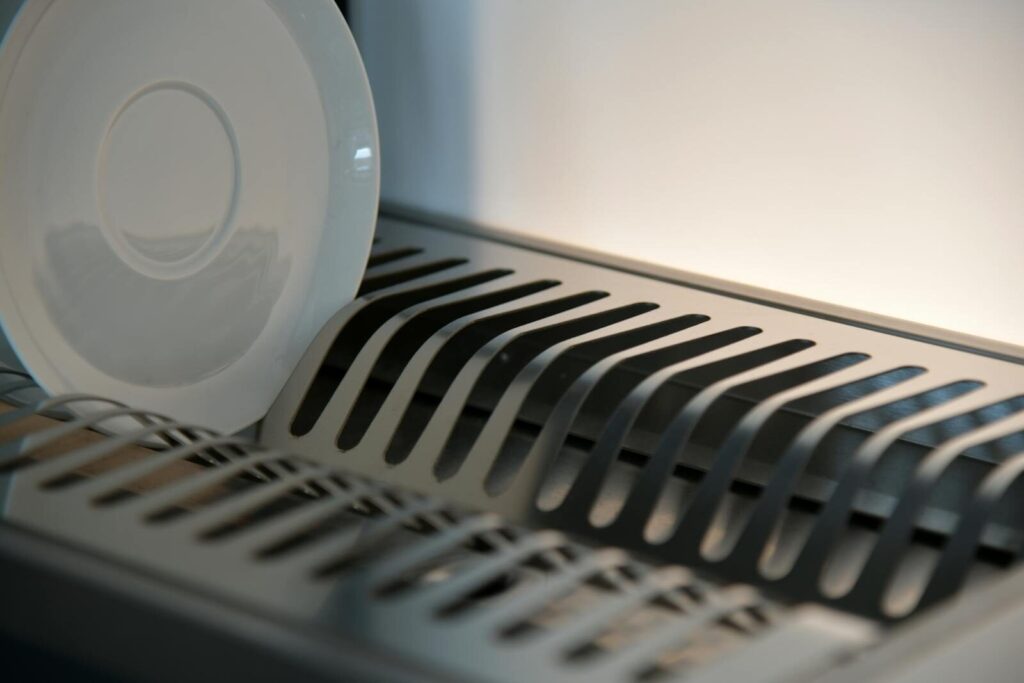 Elegant ceramic plate on a sleek metal dish rack in a modern kitchen setting.