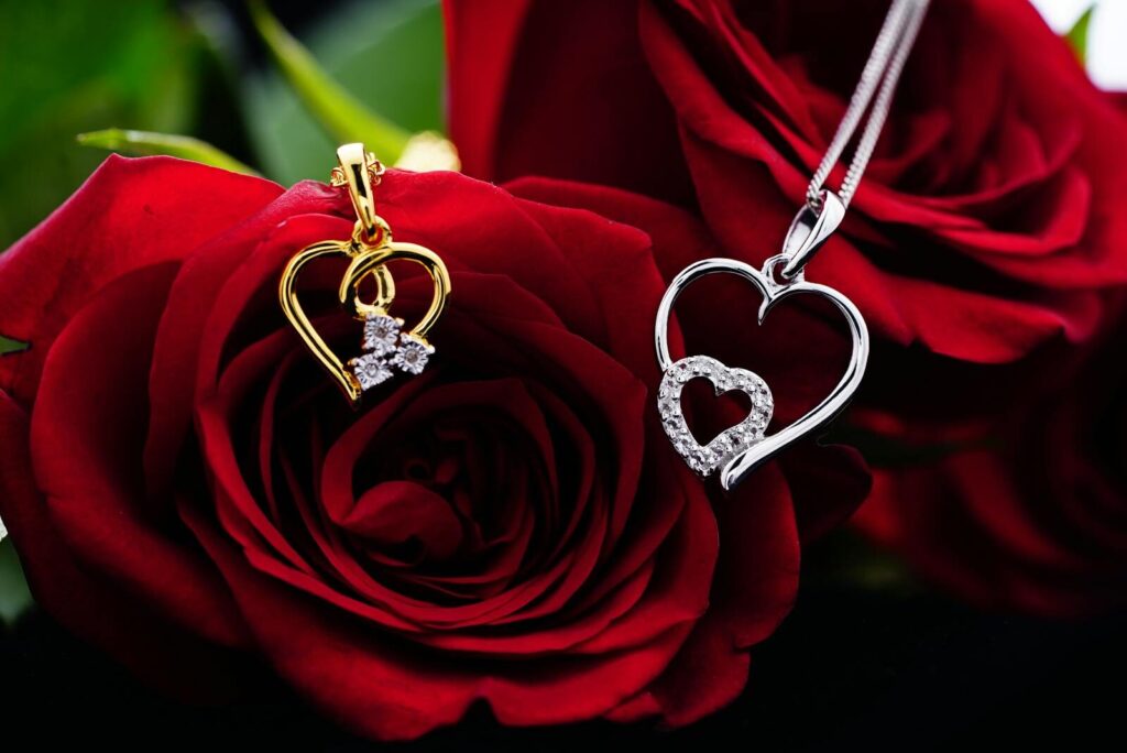 Bunch of red roses with golden and silver heart shaped pendants on necklaces