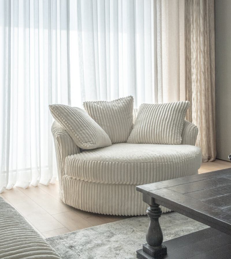 Bright living room with a round comfy chair and sheer curtains.