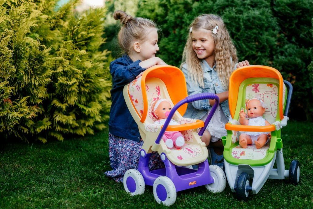 Two girls enjoy a playful day with baby dolls and strollers in the garden, capturing joy and innocence.
