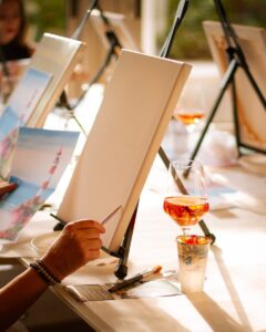 People enjoy painting and drinking wine.