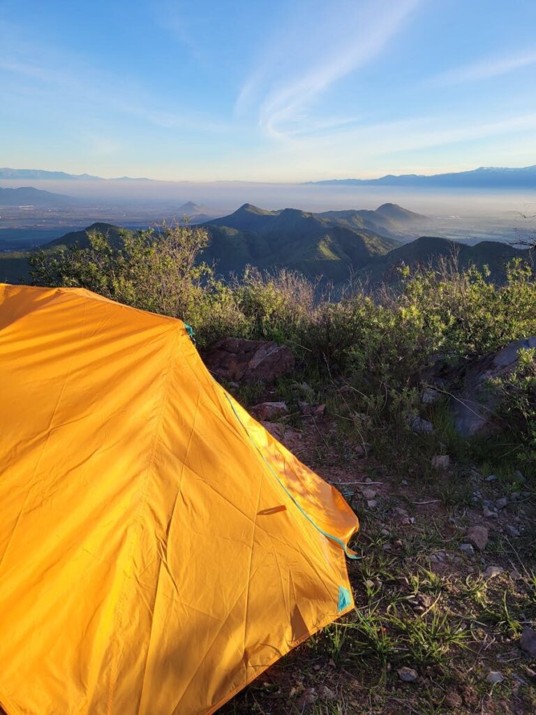 Yellow tent setup overlooking breathtaking mountains in Buin, Chile at sunrise.