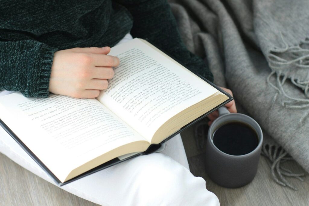 a person holding a book and a cup of coffee
