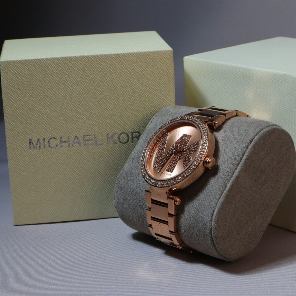 A michael kors watch sits next to its box; stylish women's watches