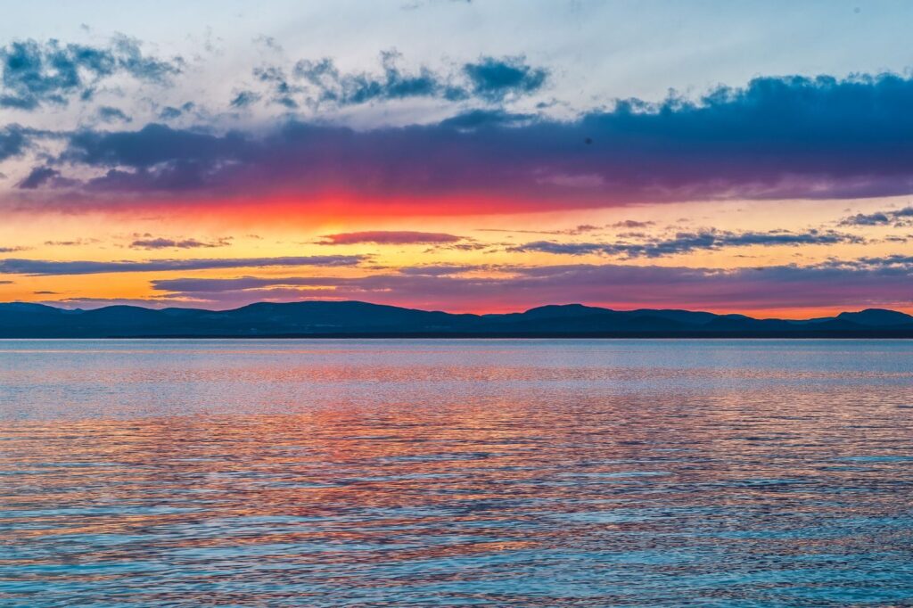 A breathtaking sunset over a serene body of water with vibrant colors and reflections.