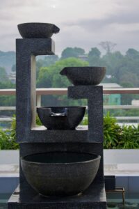 Outdoor Water FeatureS; a couple of black pots on a window sill with trees and a cloudy sky