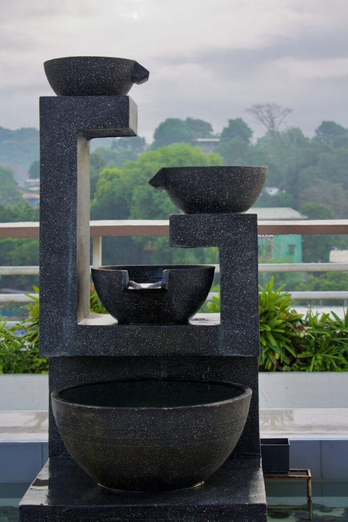 Outdoor Water FeatureS; a couple of black pots on a window sill with trees and a cloudy sky