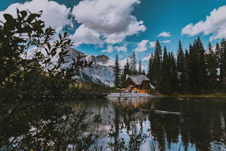 Cozy Cabin Getaways; brown wooden house near green trees and mountain under white clouds and blue sky during daytime