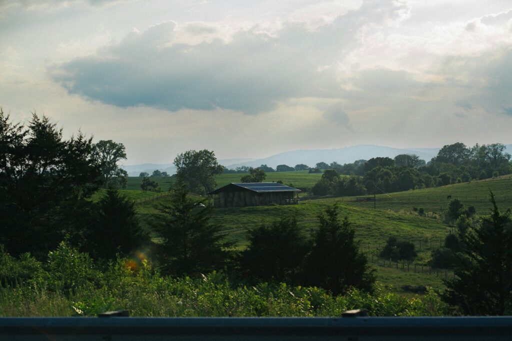 Rolling hills and a lone building under a cloudy sky.