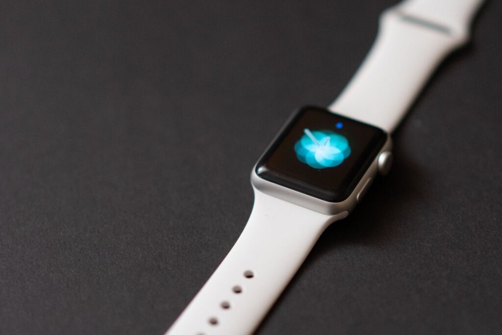 Close-up of a sleek smartwatch with a white strap on a dark surface, showcasing its digital clock display.