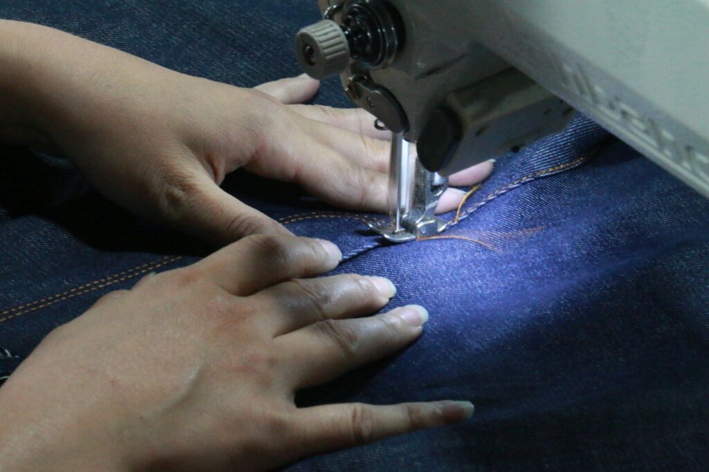 Eco-Friendly Fashion; a woman using a sewing machine to sew jeans